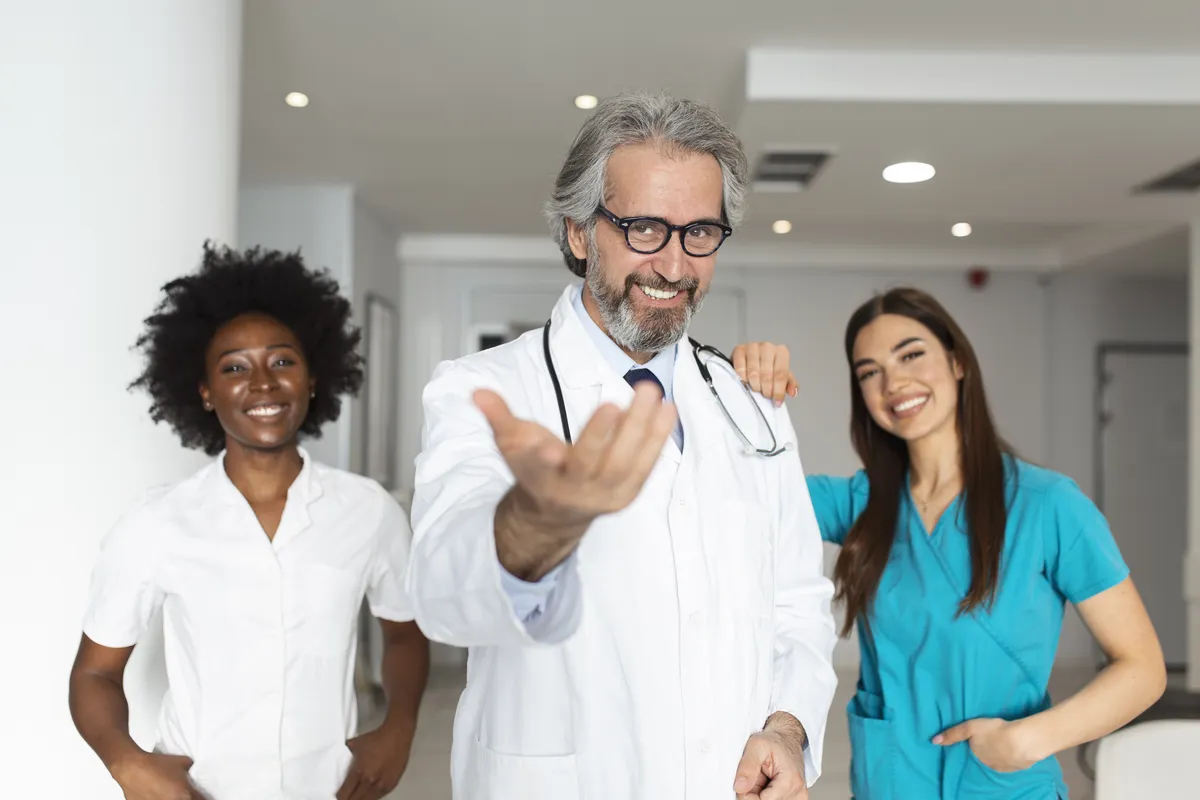 A smiling team of doctors and nurses in a clinic corridor